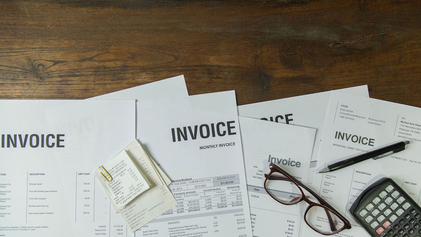 Stacked paper invoices on wooden desk